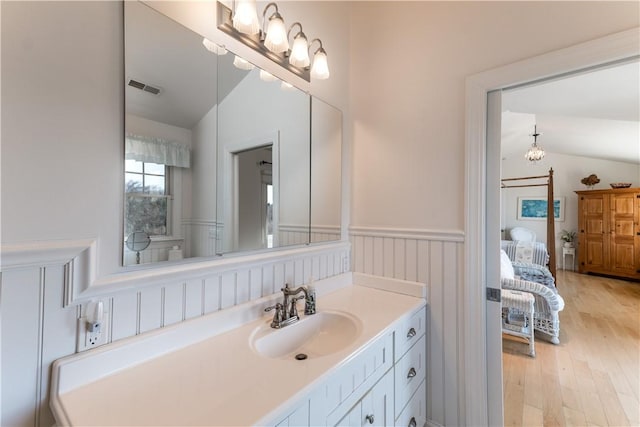 ensuite bathroom with lofted ceiling, visible vents, ensuite bathroom, and wainscoting