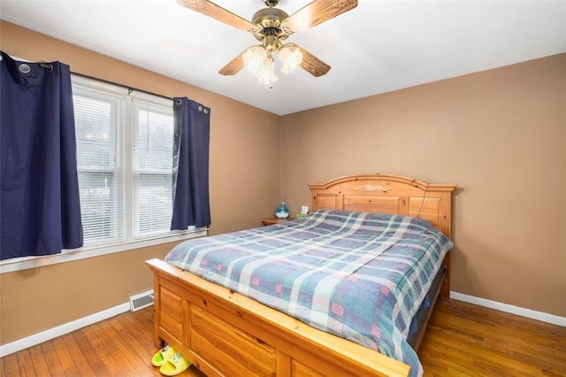 bedroom with a ceiling fan, baseboards, visible vents, and wood finished floors