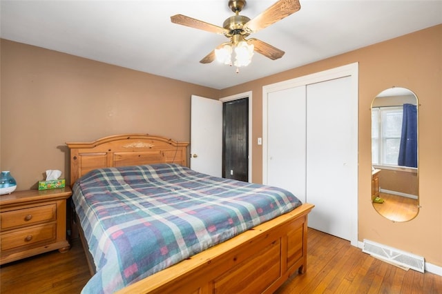 bedroom featuring a closet, visible vents, ceiling fan, wood finished floors, and baseboards