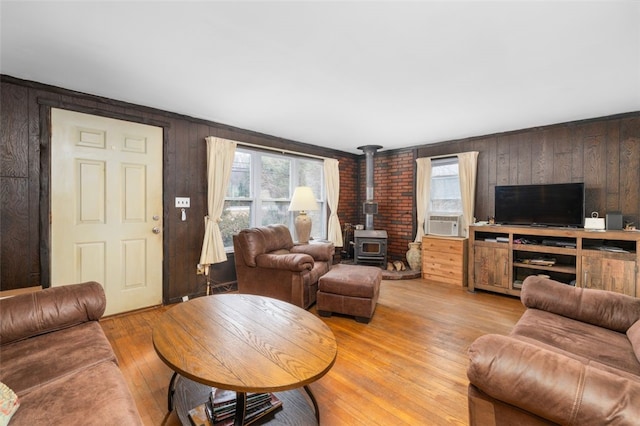 living area with light wood-style flooring, cooling unit, and a wood stove