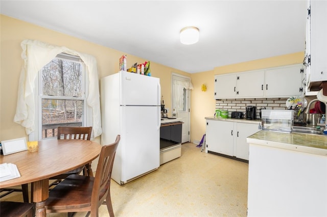 kitchen with light floors, tasteful backsplash, light countertops, white cabinets, and white appliances