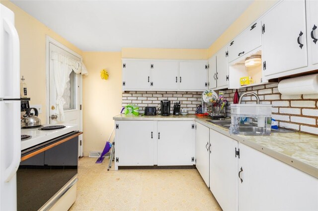 kitchen with white range with electric stovetop, white cabinets, light countertops, and backsplash