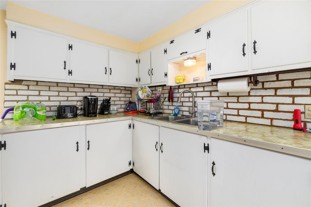 kitchen featuring light countertops, white cabinets, a sink, and light floors