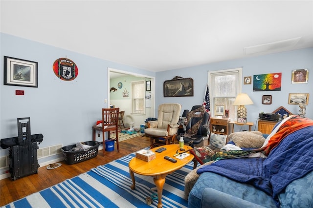 living area featuring visible vents, baseboards, and wood finished floors