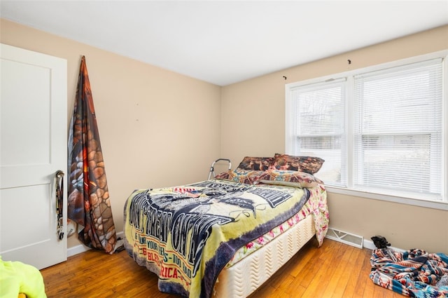 bedroom with hardwood / wood-style floors, visible vents, and baseboards