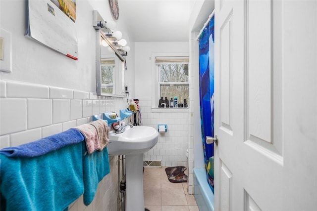 bathroom featuring a wainscoted wall, tile walls, visible vents, shower / bathtub combination with curtain, and tile patterned floors