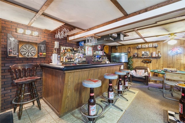 bar with brick wall, ceiling fan, wood walls, and a dry bar