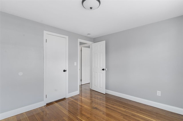 unfurnished bedroom featuring hardwood / wood-style flooring and baseboards