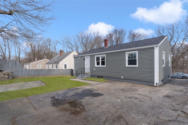 view of front of home with a front lawn, a chimney, and fence