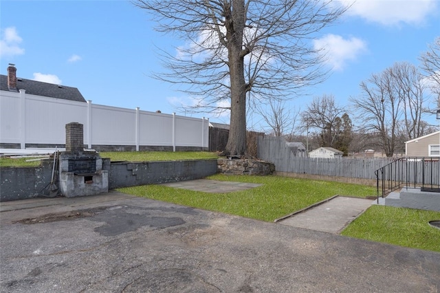 view of yard with a patio, a fireplace, and a fenced backyard