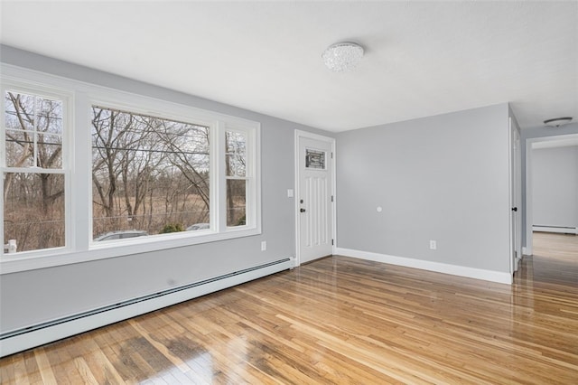 entrance foyer featuring baseboard heating, wood-type flooring, and baseboards