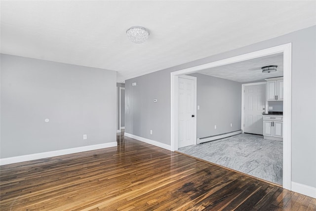 unfurnished living room featuring baseboards, a baseboard heating unit, and wood finished floors