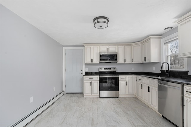 kitchen with marble finish floor, stainless steel appliances, dark countertops, a baseboard heating unit, and a sink