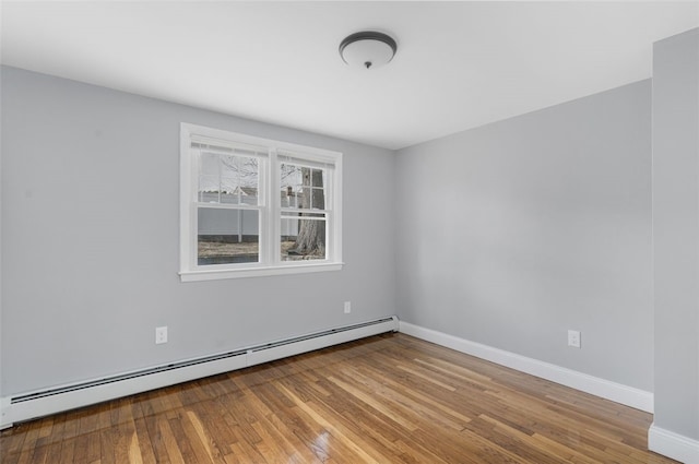 unfurnished room with a baseboard heating unit, baseboards, and hardwood / wood-style floors