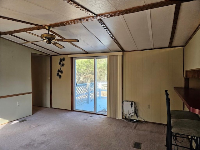 carpeted empty room featuring lofted ceiling, visible vents, and a ceiling fan