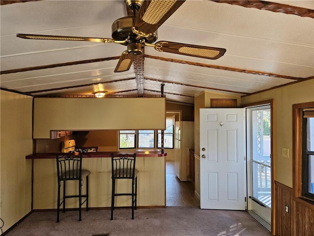 kitchen with freestanding refrigerator, lofted ceiling, dark colored carpet, and stove