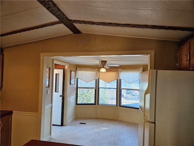 interior space featuring vaulted ceiling with beams, a textured ceiling, visible vents, a ceiling fan, and baseboards