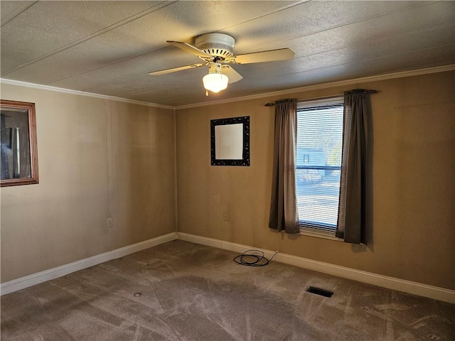 carpeted empty room featuring a ceiling fan, baseboards, visible vents, and crown molding