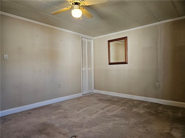 carpeted spare room featuring a ceiling fan, crown molding, and baseboards