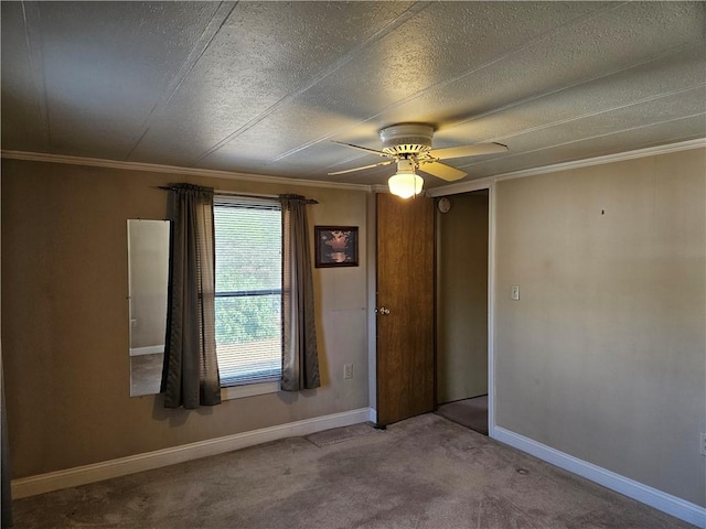 empty room with carpet floors, ceiling fan, baseboards, and ornamental molding