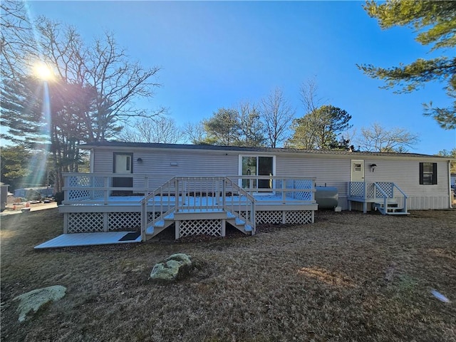 rear view of property featuring a lawn, a wooden deck, and heating fuel