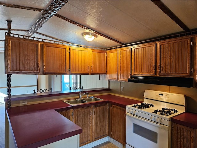 kitchen with a peninsula, a sink, ventilation hood, white gas range oven, and brown cabinetry