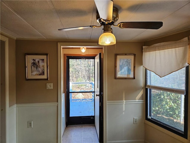 doorway to outside with a wainscoted wall and ceiling fan