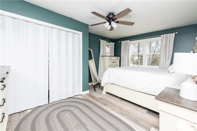 bedroom featuring ceiling fan, a closet, baseboards, and wood finished floors