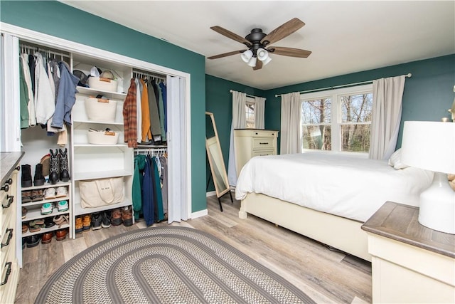 bedroom with ceiling fan, baseboards, a closet, and wood finished floors