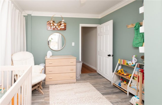 bedroom with ornamental molding, a crib, a chandelier, and light wood-style floors