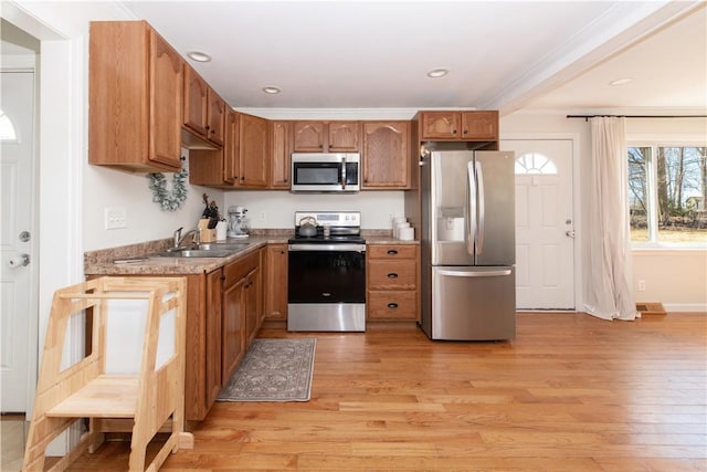 kitchen with crown molding, recessed lighting, appliances with stainless steel finishes, light wood-style floors, and a sink