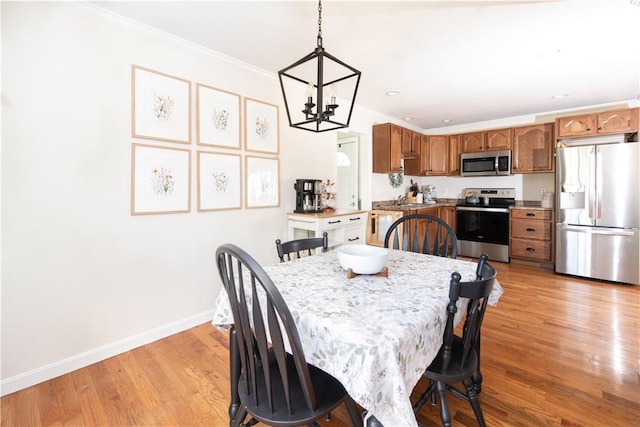 dining area featuring a chandelier, ornamental molding, light wood-type flooring, and baseboards