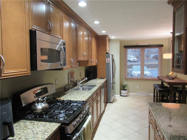 kitchen with light tile patterned floors, light stone counters, recessed lighting, a sink, and appliances with stainless steel finishes