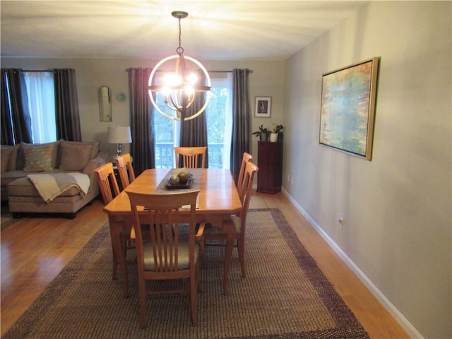 dining space featuring light wood-type flooring, baseboards, and a notable chandelier