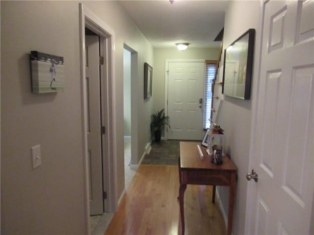 hall featuring light wood finished floors and baseboards