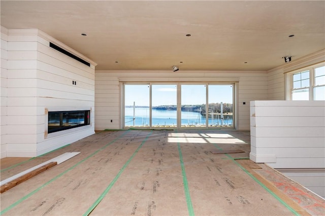 unfurnished living room featuring a water view and a glass covered fireplace