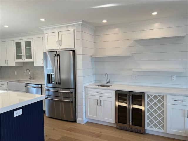 kitchen featuring light countertops, beverage cooler, appliances with stainless steel finishes, and a sink