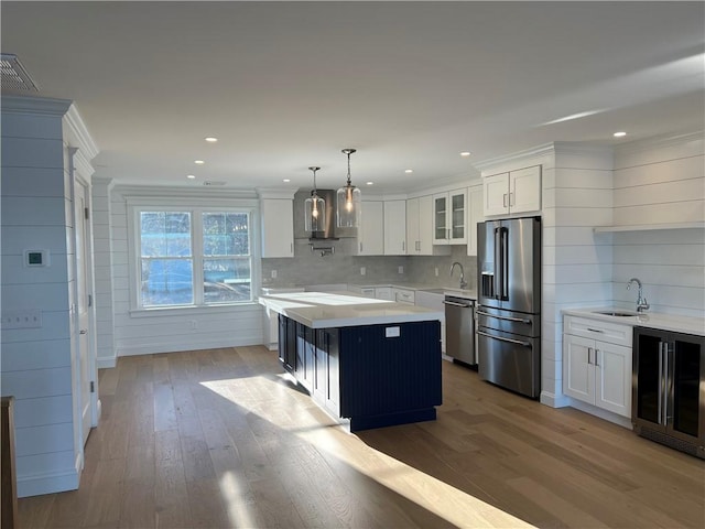 kitchen with beverage cooler, light countertops, appliances with stainless steel finishes, white cabinetry, and a sink