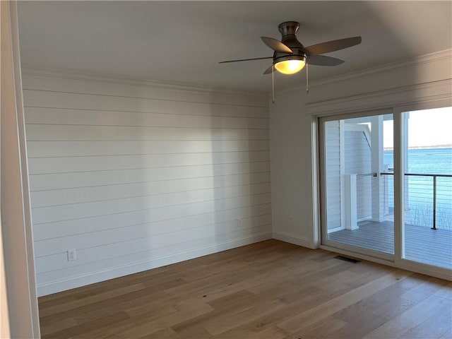 spare room with a ceiling fan, crown molding, baseboards, and wood finished floors