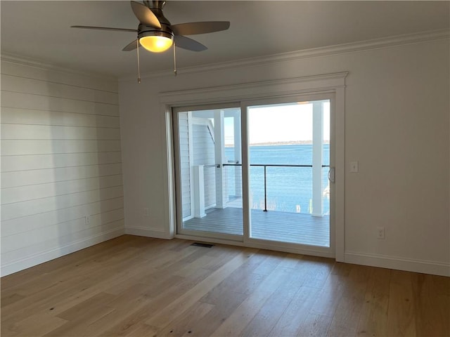 spare room with visible vents, wood finished floors, baseboards, and ornamental molding