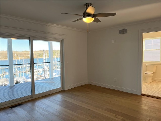 empty room featuring visible vents, baseboards, ornamental molding, and light wood-style flooring