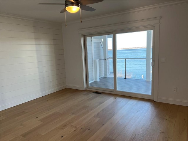 spare room with crown molding, baseboards, and light wood finished floors