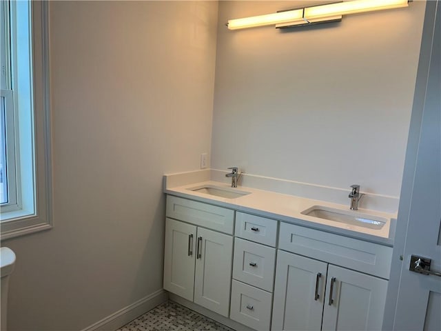 full bath with double vanity, toilet, baseboards, and a sink