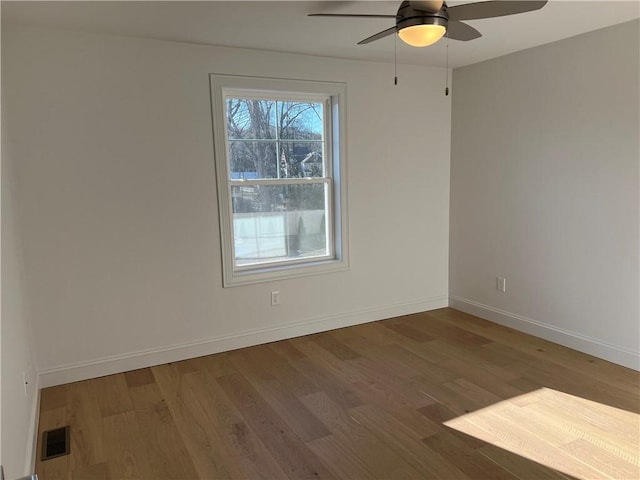 unfurnished room featuring ceiling fan, wood finished floors, visible vents, and baseboards