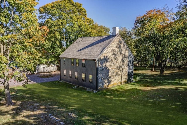 view of side of home featuring a lawn, a chimney, and a shingled roof