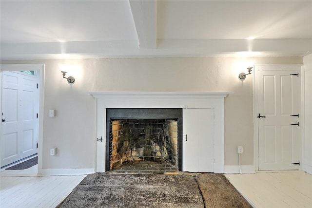 room details featuring baseboards, a fireplace with flush hearth, beam ceiling, and wood finished floors