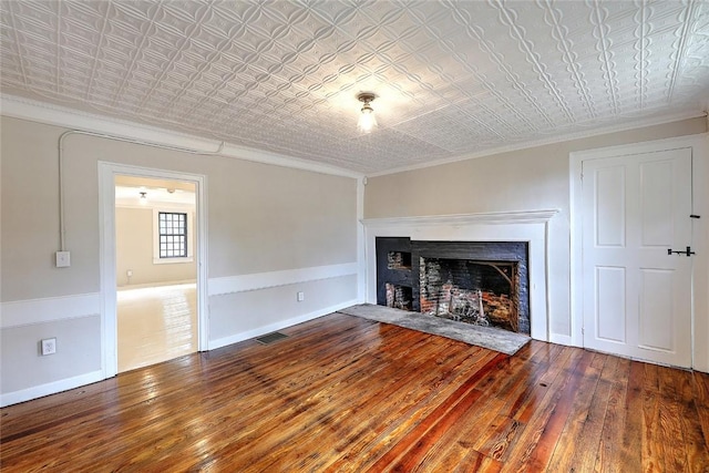 unfurnished living room with a fireplace with flush hearth, an ornate ceiling, and hardwood / wood-style floors