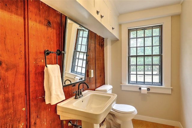 bathroom featuring toilet, baseboards, and a sink