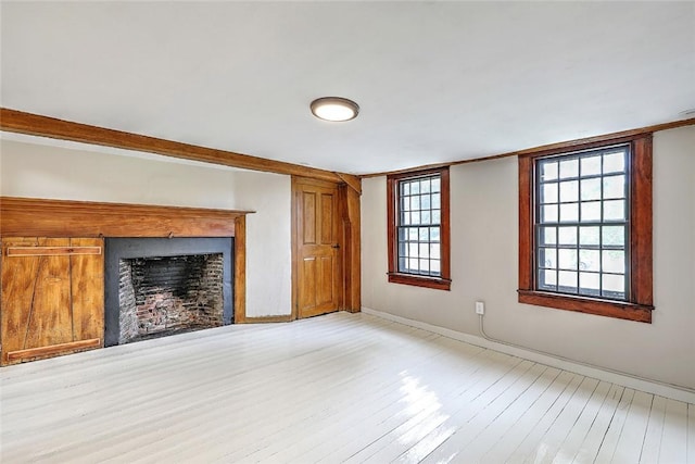 unfurnished living room with baseboards, a fireplace, and hardwood / wood-style flooring