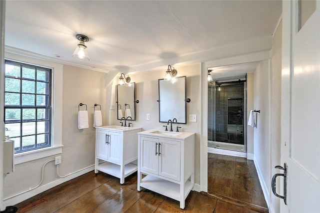 bathroom with a sink, two vanities, a stall shower, and hardwood / wood-style flooring